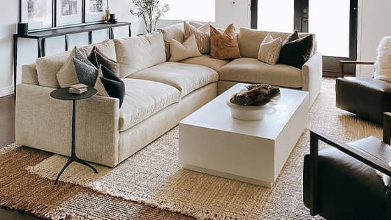 Two handcrafted jute rugs layered in a living room under a beige couch. 