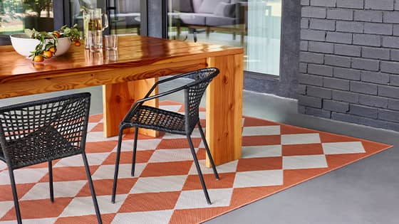 Harlequin high-performance outdoor rug under an outdoor dining table.