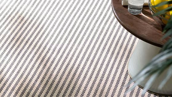 A striped textured rug sits under a table.