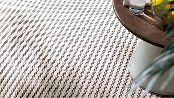 A striped textured rug sits under a table. 